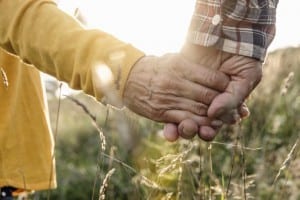 close up of mature couple hands holding in meadow